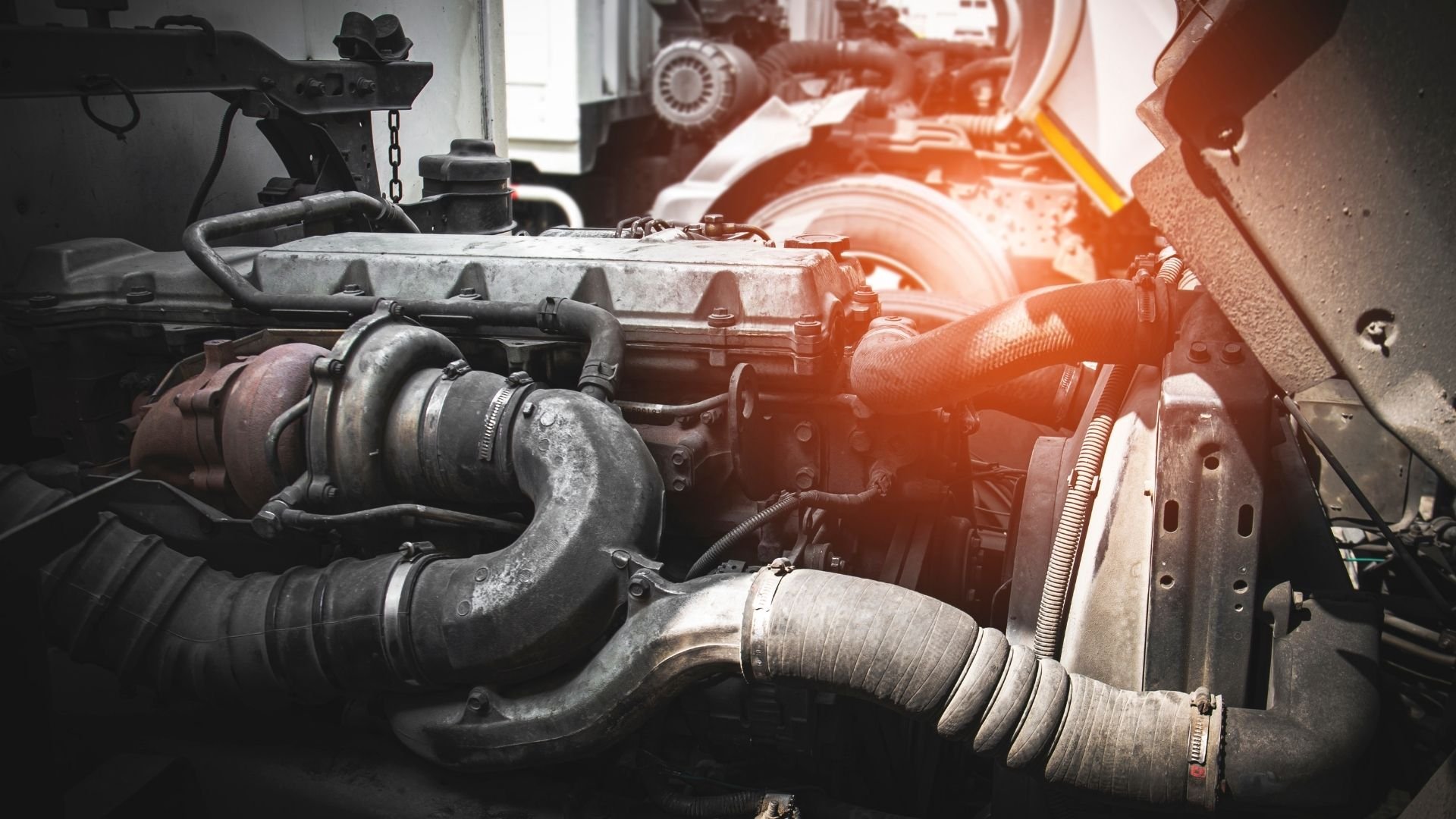 Engine block with turbocharger and hoses in automotive workshop with warm lighting