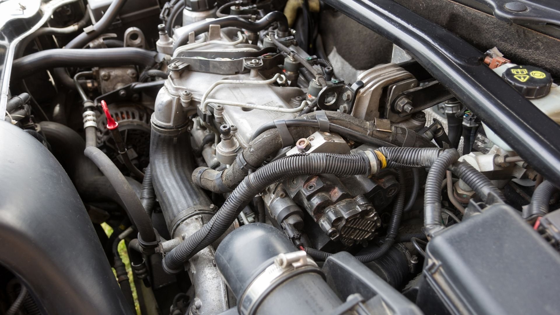 Close-up of car engine bay showing metal components, hoses, and mechanical parts.